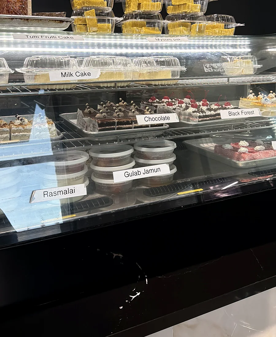 Bakery case with milk cake, chocolate cake, black forest cake, rasmalai and gulab jamun
