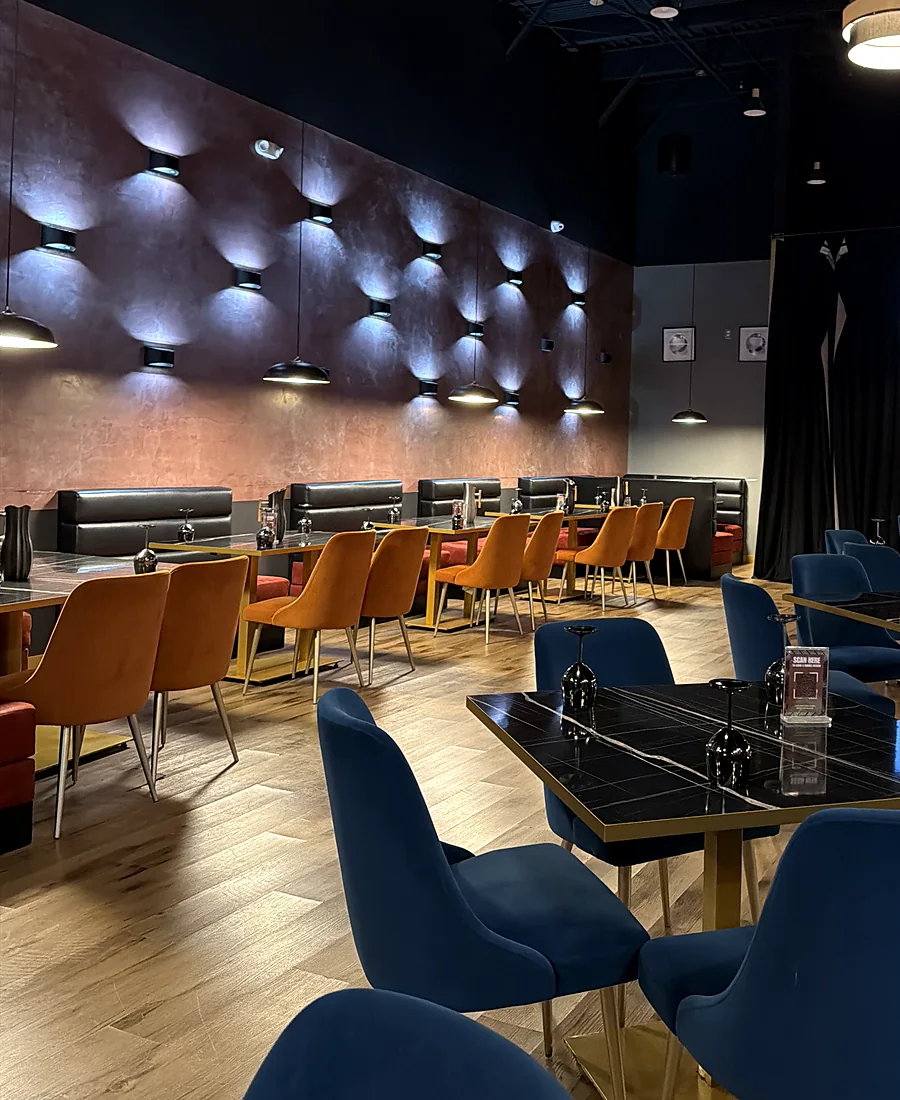 Dining room with blue velvet chairs, black tables and lit wall booths