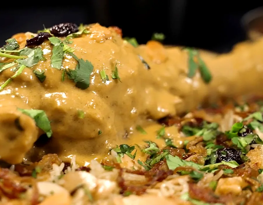 Biryani topped with a slow-cooked bone-in piece in golden gravy